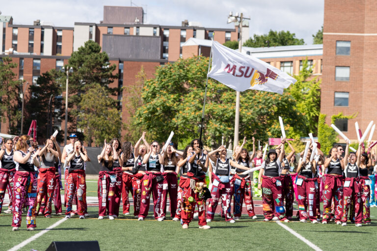 MSU Maroons Welcome Week Reps waving flag on Ron Joyce Stadium, McMaster University, Hamilton, Ontario, Canada